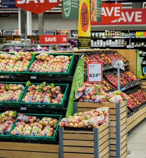 Colorful produce aisle in a supermarket showcasing fresh apples with discount signage.